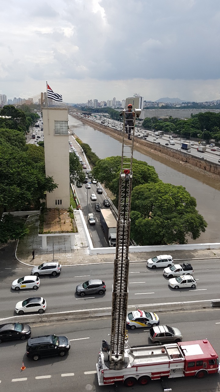 Bombeiro no alto da escada realiza trocada bandeira 